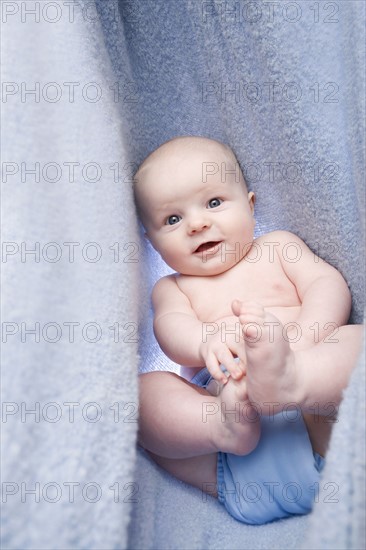 Portrait of baby boy (6-11 months) in bedclothes. Photo : Noah Clayton