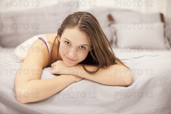 Portrait of young woman relaxing on bed. Photo : Mike Kemp