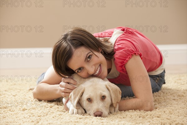 Portrait of woman embracing Labrador on carpet. Photo : Mike Kemp