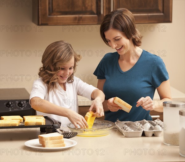 Mother preparing breakfast with daughter (10-11) in kitchen. Photo : Mike Kemp