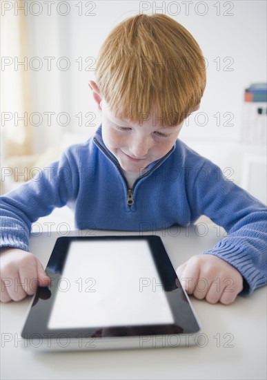 Portrait of boy (8-9) with e-book. Photo : Jamie Grill Photography