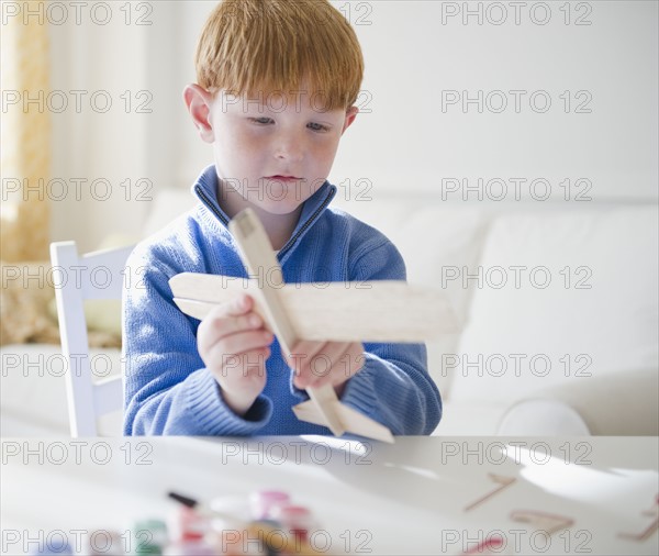 Portrait of boy (8-9) with model airplane. Photo : Jamie Grill Photography