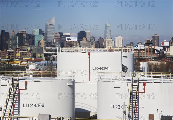 USA, New York City, Oil storage tanks in refinery with Manhattan skyline in background. Photo : fotog