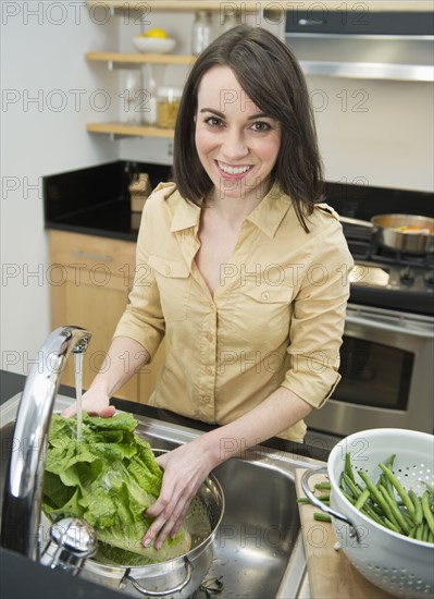 Portrait of young woman preparing food in kitchen.