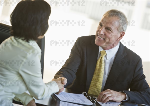 Businesswoman and businessman shaking hands.
