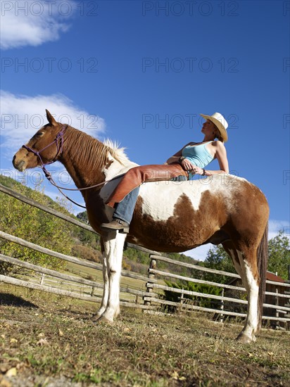 USA, Colorado, Cowgirl relaxing with horse on ranch. Photo : John Kelly