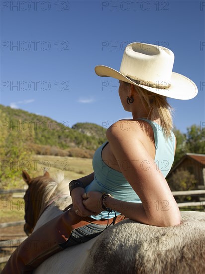 USA, Colorado, Cowgirl relaxing with horse on ranch. Photo : John Kelly