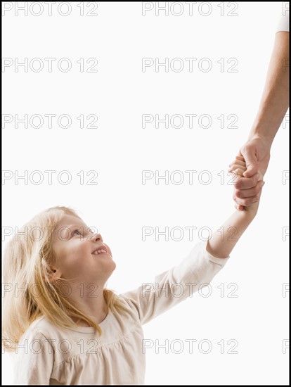 Studio shot of girl (2-3) holding adult's hand. Photo : Mike Kemp