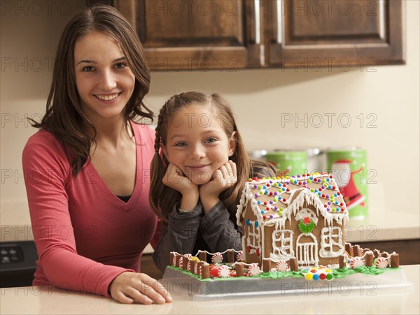 Portrait of two sisters (6-7, 18-19) by gingerbread house. Photo : Mike Kemp