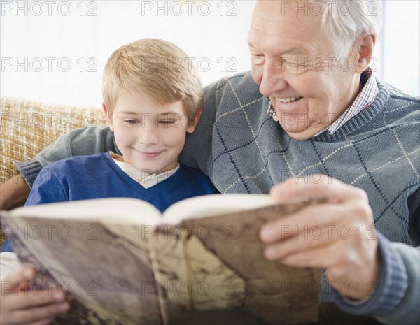 Grandfather and grandson (8-9) reading book. Photo : Jamie Grill Photography