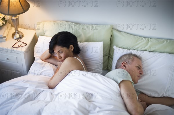 Mature couple laying in bed after argument.