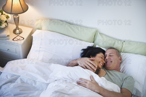 Happy mature couple laying in bed.