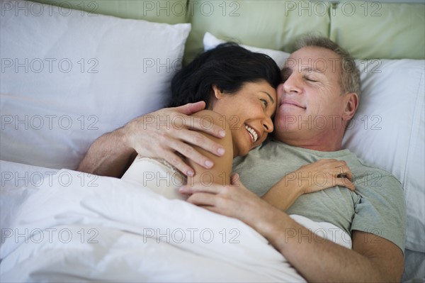 Happy mature couple laying in bed.