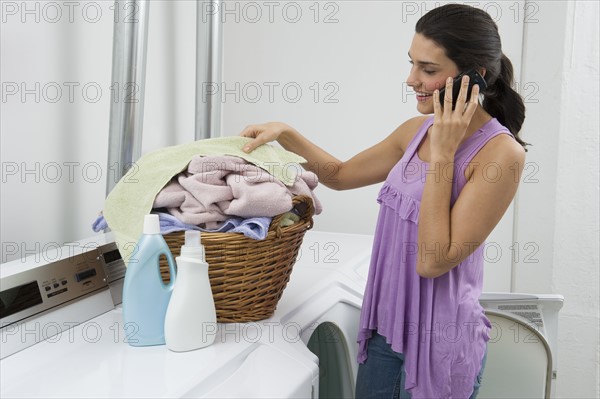 Woman doing laundry and talking on phone.