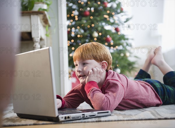 Boy (8-9) wearing headphones, using laptop. Photo : Jamie Grill Photography