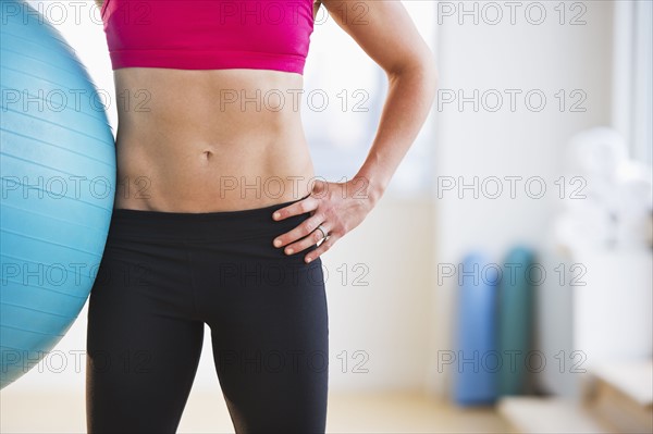 Midsection of woman holding fitness ball. Photo : Daniel Grill