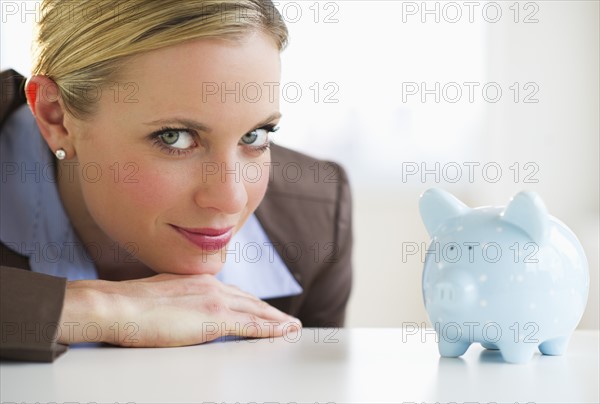 Portrait of businesswoman with piggy bank. Photo : Daniel Grill