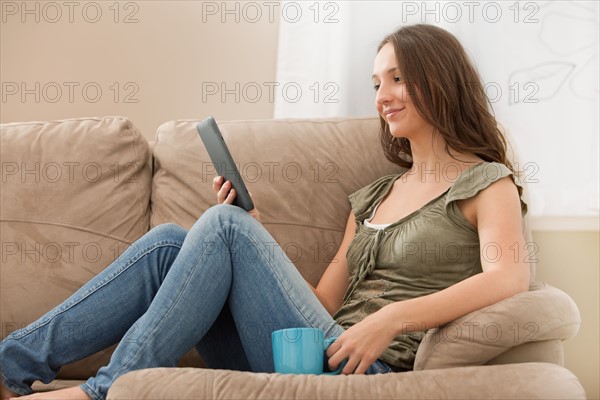 Young woman reading e-book on digital tablet. Photo : Mike Kemp