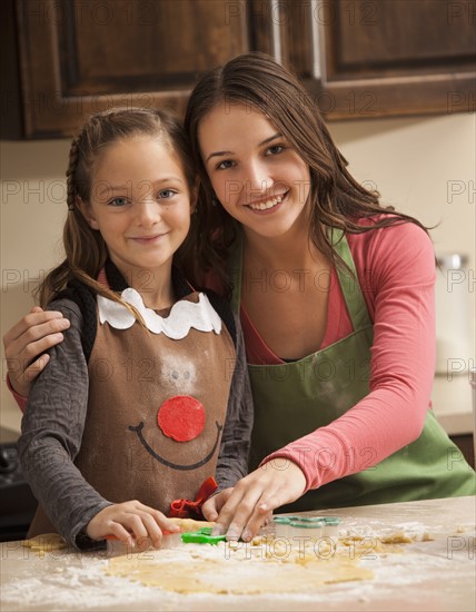 Portrait of two sisters (6-7, 18-19) making cookies. Photo : Mike Kemp