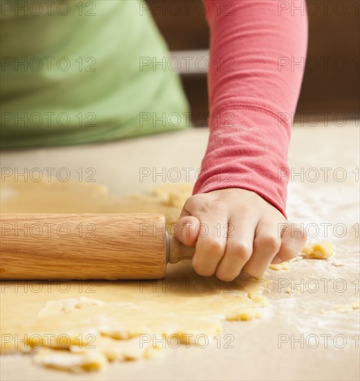 Close-up of girl (6-7) rolling dough. Photo : Mike Kemp