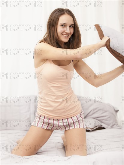Young woman pillow-fighting. Photo : Mike Kemp