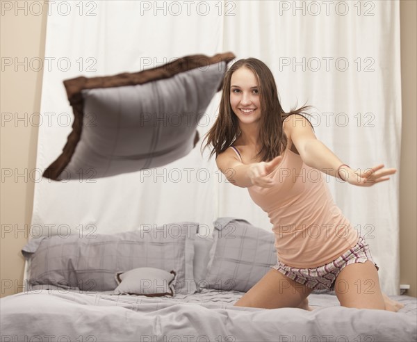 Young woman pillow-fighting. Photo : Mike Kemp