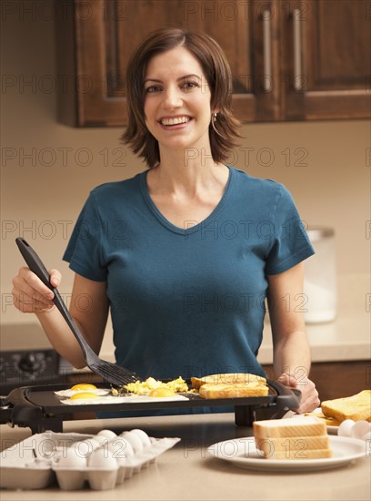 Portrait of woman preparing breakfast in kitchen. Photo : Mike Kemp