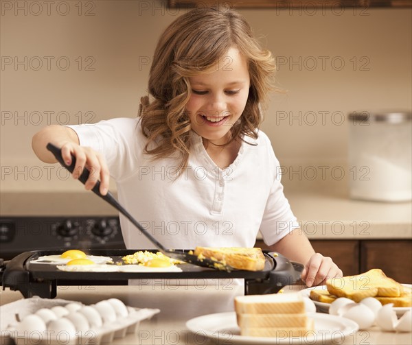 Girl (10-11) preparing breakfast in kitchen. Photo : Mike Kemp