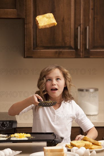 Girl (10-11) flipping toast in kitchen. Photo : Mike Kemp