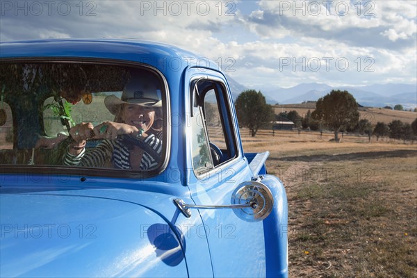 USA, Colorado, Carbondale, Cowgirl driving old fashioned pickup truck in field. Photo : Noah Clayton