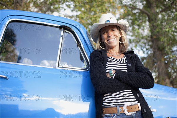 USA, Colorado, Carbondale, Portrait of cowgirl with old fashioned pickup truck. Photo : Noah Clayton