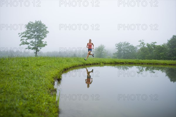 USA, Vermont, Landgrove, Woman jogging by lake. Photo : Noah Clayton