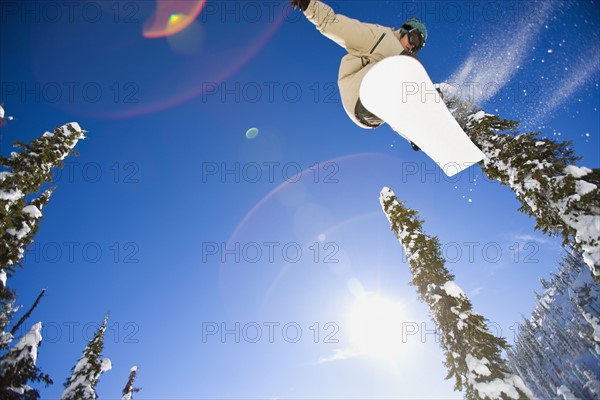 USA, Montana, Whitefish, Young man snowboarding in forest. Photo : Noah Clayton