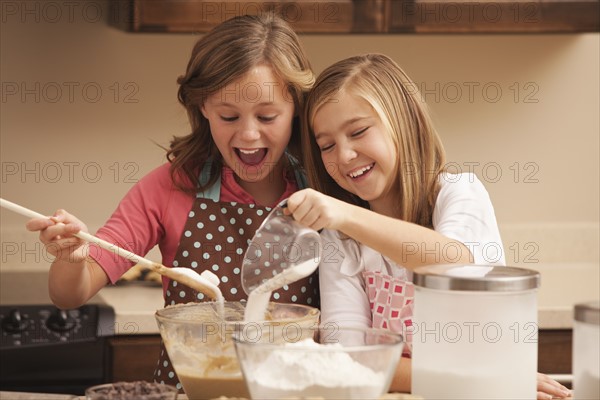 Two girls (10-11) baking in kitchen. Photo : Mike Kemp