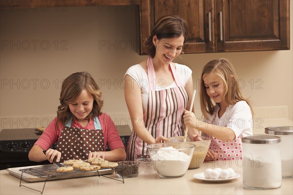 Mother baking with daughters (10-11) in kitchen. Photo : Mike Kemp