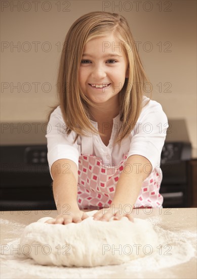 Portrait of girl (10-11) kneading dough in kitchen. Photo : Mike Kemp