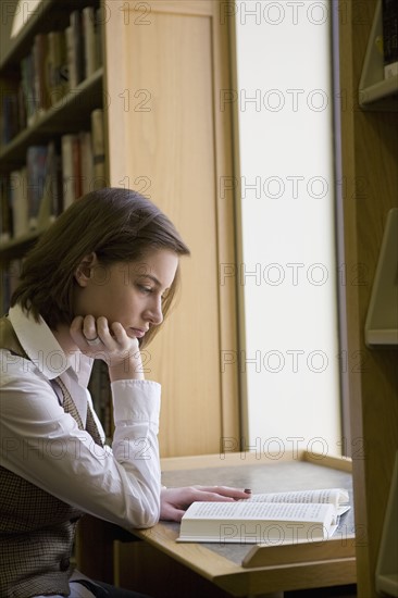 USA, New Jersey, female student reading book in library. Photo : Chris Hackett