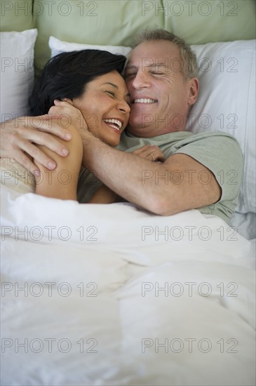 Happy mature couple laying in bed.