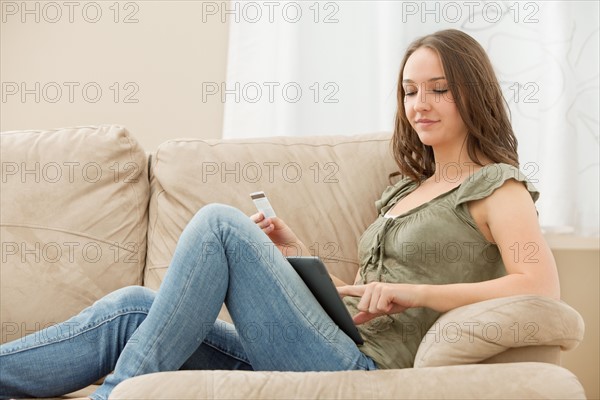 Young woman using tablet and holding credit card. Photo : Mike Kemp