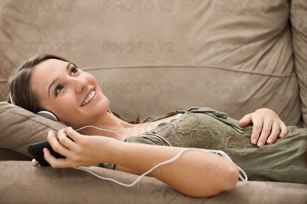 Young woman listening music from mp3 player. Photo : Mike Kemp