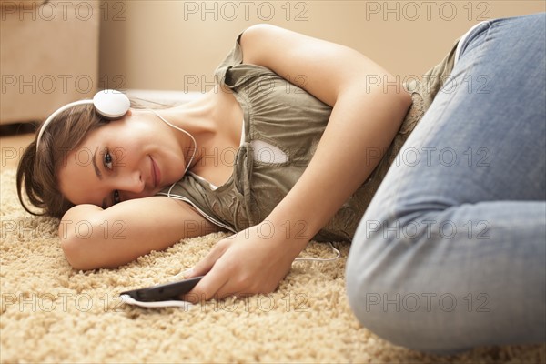 Young woman listening music from mp3 player. Photo : Mike Kemp