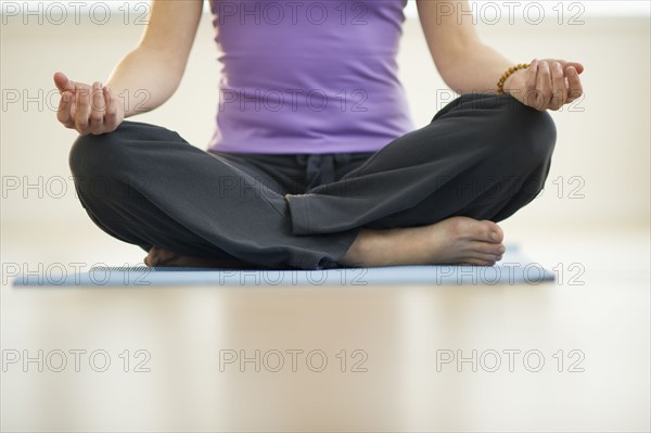 Young woman meditation in lotus position, low section.