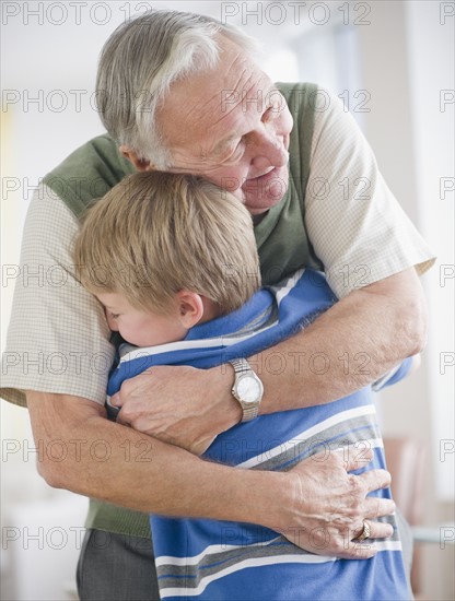 Grandfather hugging grandson (8-9) . Photo : Jamie Grill Photography
