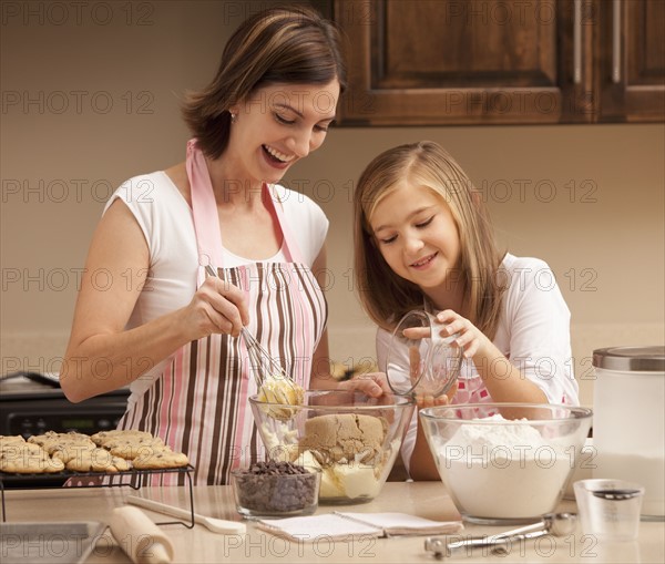 Mother baking with daughter (10-11) in kitchen. Photo : Mike Kemp