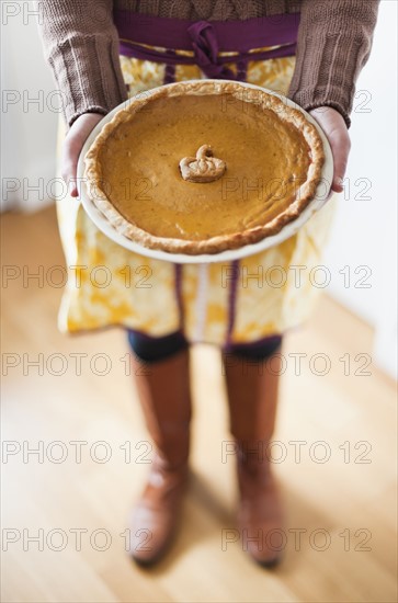 Close up of woman holding pumpkin pie.