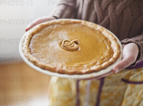 Close up of woman holding pumpkin pie.