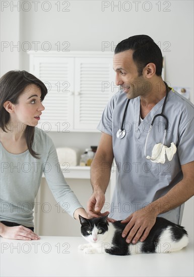 Woman and vet stroking cat in pet clinic.