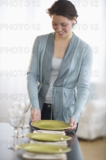 Young woman setting table.