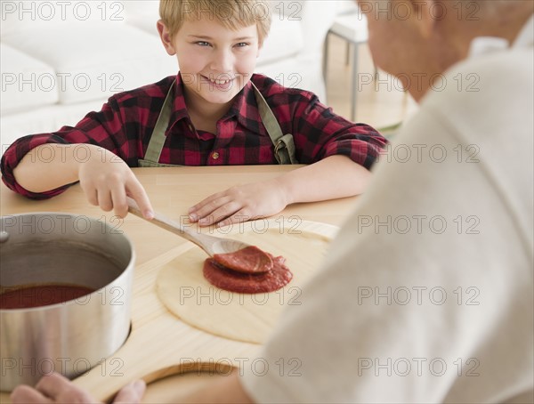 Grandfather and grandson (8-9) preparing pizza. Photo : Jamie Grill Photography