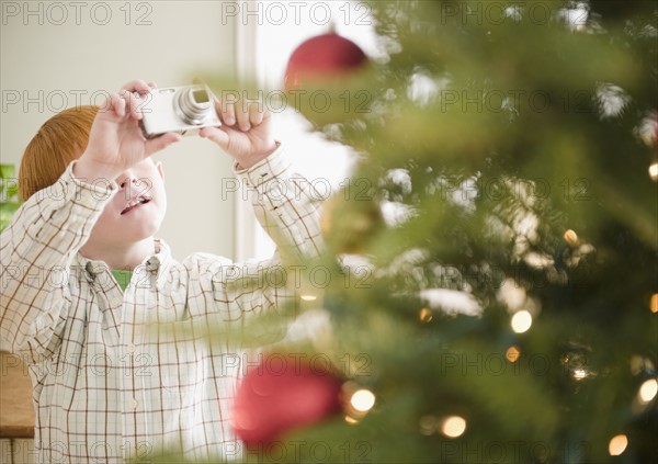 Boy (8-9) photographing Christmas tree. Photo : Jamie Grill Photography